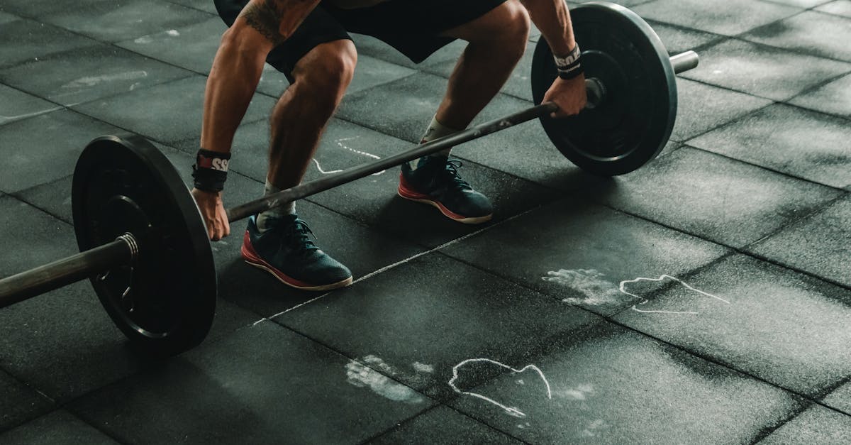 A muscular man in a gym preparing to lift a heavy barbell, showcasing strength and fitness.